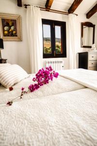 Un dormitorio con una cama blanca con flores púrpuras. en Finca Rural Son Rabassa, en Sant Joan