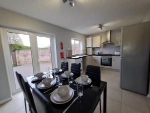 a dining room with a table and chairs and a kitchen at 3 Bed House with Garage, NR BPW & Brecon Beacons National Park in Cefn-coed-y-cymmer