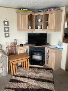 a living room with a television and a fireplace at Gaz goldengates in Kinmel Bay