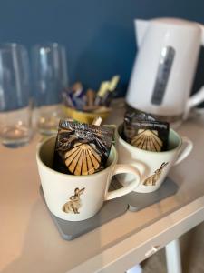 two coffee cups sitting on top of a counter at Tegfan -The Anglesey Townhouse in Caernarfon