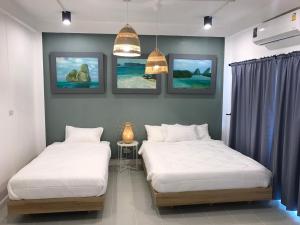 2 Betten in einem Zimmer mit Gemälden an der Wand in der Unterkunft Baan Suandao Wat Arun in Bangkok