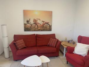 a living room with a red couch and a painting of bikes at Vistas Melenara by CanariApartment - Beachfront Apartments with Balcony and Fast WiFi in Telde