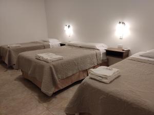 three beds in a room with towels on them at Betania in Paracas