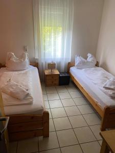 2 Betten in einem kleinen Zimmer mit Fenster in der Unterkunft Gaststätte Pütz in Siegen