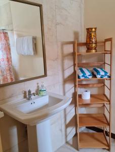 a bathroom with a sink and a mirror and a shelf at Sandpiper Beach Apartments in Palm-Eagle Beach