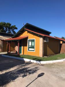uma pequena casa amarela com um telhado vermelho em Casa com piscina para família em Florianópolis