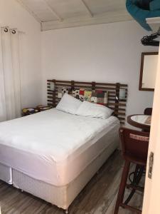 um quarto com uma grande cama branca e uma mesa em Casa com piscina para família em Florianópolis