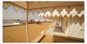 a beach with an umbrella on the sand at Jaisalmer Desert Resort in Jaisalmer
