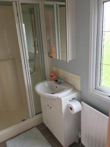 a white bathroom with a sink and a shower at Willerby in Leysdown-on-Sea