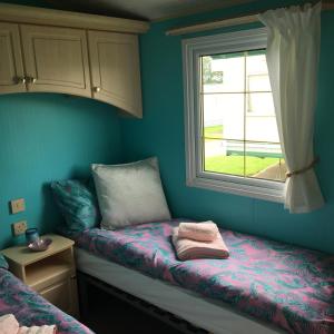 a small room with a bed and a window at Willerby in Leysdown-on-Sea