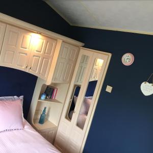 1 dormitorio con 1 cama, armario y espejo en Willerby, en Leysdown-on-Sea