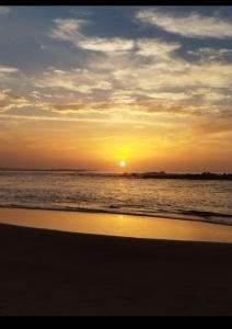 una puesta de sol en una playa con el océano en Appartement Dahomey Bouznika, en Bouznika