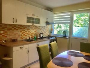 a kitchen with a table and a sink and a stove at Apartman Bloom in Osijek