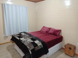 um quarto com uma cama com lençóis roxos e uma janela em A Casa é Sua! em Urubici