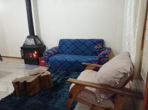 ein Wohnzimmer mit einem Sofa, einem Stuhl und einem Kamin in der Unterkunft A Casa é Sua! in Urubici