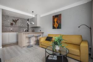 a living room with a yellow couch and a kitchen at TS Nowe Miasto in Szczecin