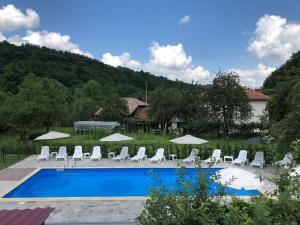 a swimming pool with chairs and umbrellas at Baba Stana Houses in Apriltsi