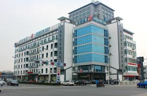 Jinjiang Inn - Suzhou Wuzhong Baodai West Road في سوتشو: مبنى كبير فيه سيارات تقف امامه