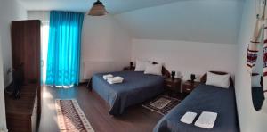- une chambre avec 2 lits et des rideaux bleus dans l'établissement Agropensiunea Pe Poderei, à Cupşeni