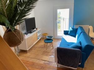 salon z niebieską kanapą i telewizorem w obiekcie Le Clos Bellevue w mieście Tressan