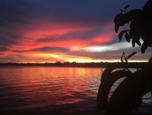 um pôr-do-sol sobre uma massa de água com em Casa do Lago Hospedaria em Brasília