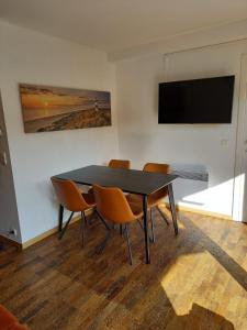 a dining room table with chairs and a flat screen tv at appartement zee zon en zwem in Bredene-aan-Zee