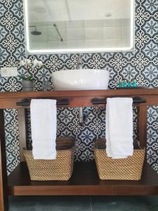 een badkamer met een wastafel, een spiegel en manden bij Olive Tree Bed and Breakfast in Olvera