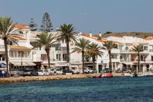 a group of buildings and palm trees next to a body of water at Apartamentos Gabriel Sans in Fornells