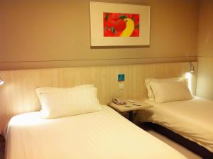 a hotel room with two beds and a picture on the wall at Jinjiang Inn - Suzhou Executive Center Hotel in Suzhou