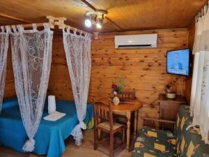 Habitación en una cabaña de madera con mesa y TV en Cabañas El Robledo, en El Robledo