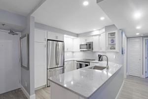 Una cocina con gabinetes blancos y un refrigerador de acero inoxidable. en Beachfront condo with heated pool, gym and pickleball, en Marco Island