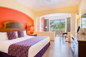 a hotel room with a bed and a balcony at Iberostar Selection Rose Hall Suites in Montego Bay