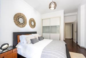 Schlafzimmer mit einem weißen Bett und einem Wandspiegel in der Unterkunft City View Apartment by Madeira Sun Travel in Funchal
