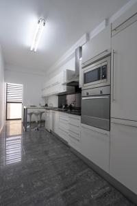 eine große Küche mit weißen Geräten und einem Tisch in der Unterkunft City View Apartment by Madeira Sun Travel in Funchal