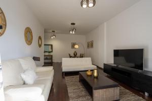 ein Wohnzimmer mit einem weißen Sofa und einem Flachbild-TV in der Unterkunft City View Apartment by Madeira Sun Travel in Funchal