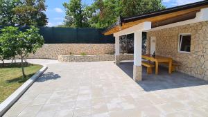 um pátio com um banco de madeira ao lado de uma parede de pedra em House for vacation Runac em Imotski