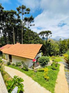 a small house with an orange tile roof at Chalé Recanto dos Pinheiros in Monte Verde