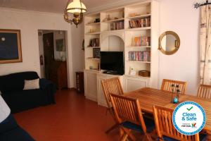 a living room with a table and chairs and a tv at Cezimbra Guest House in Sesimbra