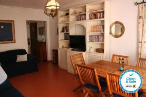 - un salon avec une table, des chaises et une télévision dans l'établissement Cezimbra Guest House, à Sesimbra