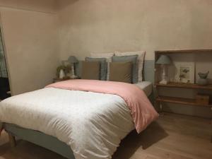 1 dormitorio con 1 cama con manta rosa en Gîte Au petit bonheur, en Châteldon