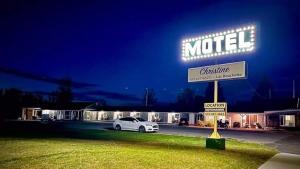 un cartel de motel con un coche aparcado en un estacionamiento en motel Christine, en Lac-Bouchette