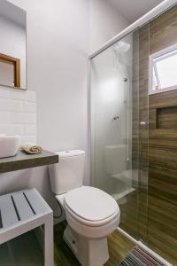 a bathroom with a toilet and a glass shower at Pousada Caminho Nômade in Garopaba