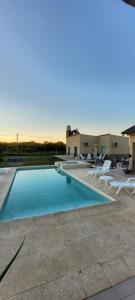 une piscine avec des chaises blanches et une maison dans l'établissement El Coronillo - Lodge, à Concepción del Uruguay 13 autres photos