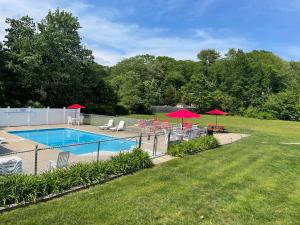 a swimming pool with chairs and umbrellas in a yard at Kennebunkport Motor Lodge in Kennebunkport