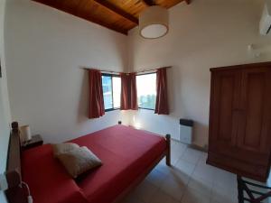 a bedroom with a red bed and a window at Ayres Del Rio Uruguay in Colón