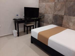 a bedroom with a bed and a desk with a television at Departamentos X`Kanlol in Izamal