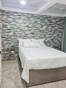 Apartamento Turistico Soul في La Loma: سرير في غرفة نوم مع جدار من الطوب