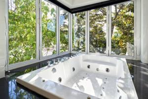 a large white tub in a bathroom with windows at Villa Ginborn 5 bedroom Pool Villa with Sea View in Kata Beach in Kata Beach