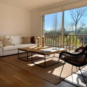 uma sala de estar com um sofá, uma mesa e cadeiras em Oak Park Carrasco em Montevidéu