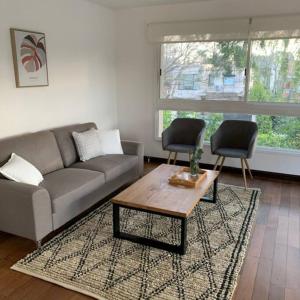 uma sala de estar com um sofá, uma mesa e 2 cadeiras em Oak Park Carrasco em Montevidéu
